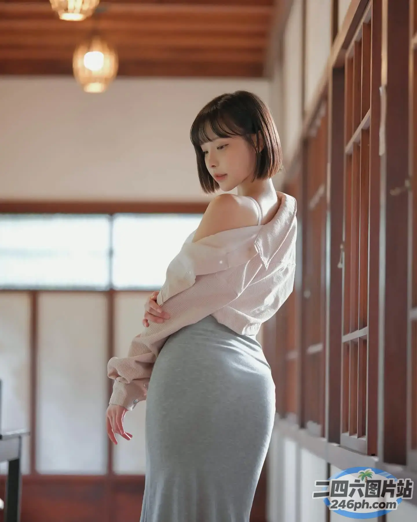 一个穿着裙子和白衬衫的女人站在一个房间里