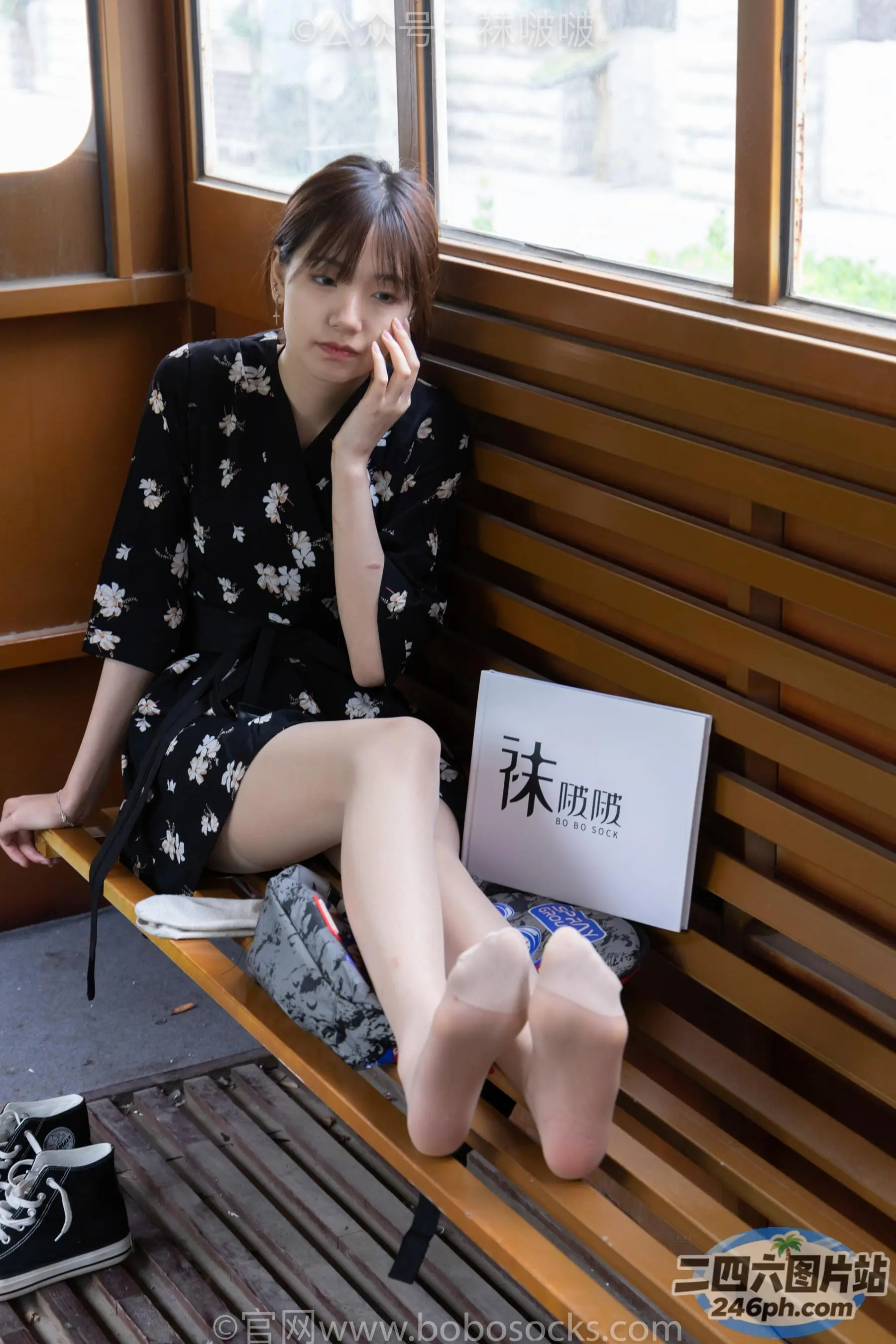 阿拉菲坐在长凳上，手里拿着笔记本电脑和手机
