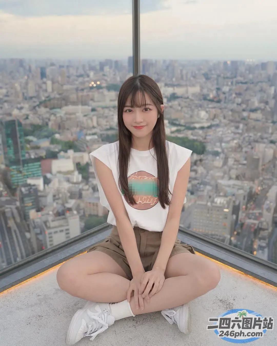 一位女士坐在窗前的窗台上，可欣赏城市景观