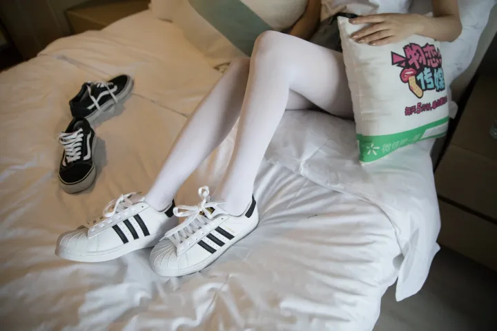 床上坐着一个女人，手里拿着包和鞋子