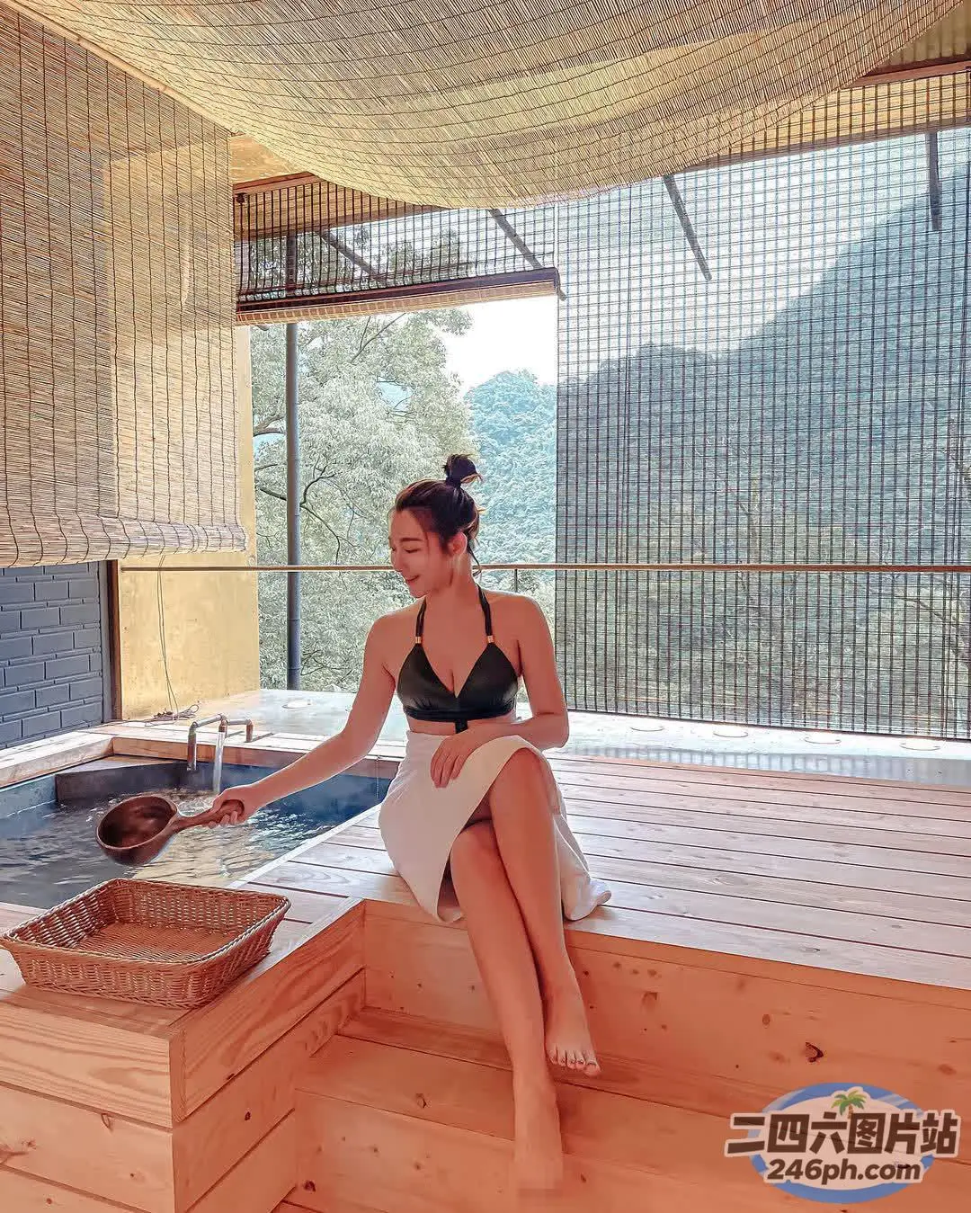穿着黑色比基尼的女人坐在热水浴缸的木凳上