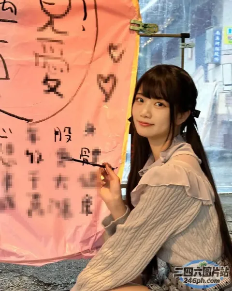 地上坐着一个女人，手里拿着一把刷子和一条粉红色的横幅