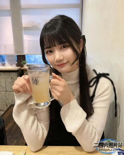 有个女人坐在桌子旁，手里拿着一杯饮料