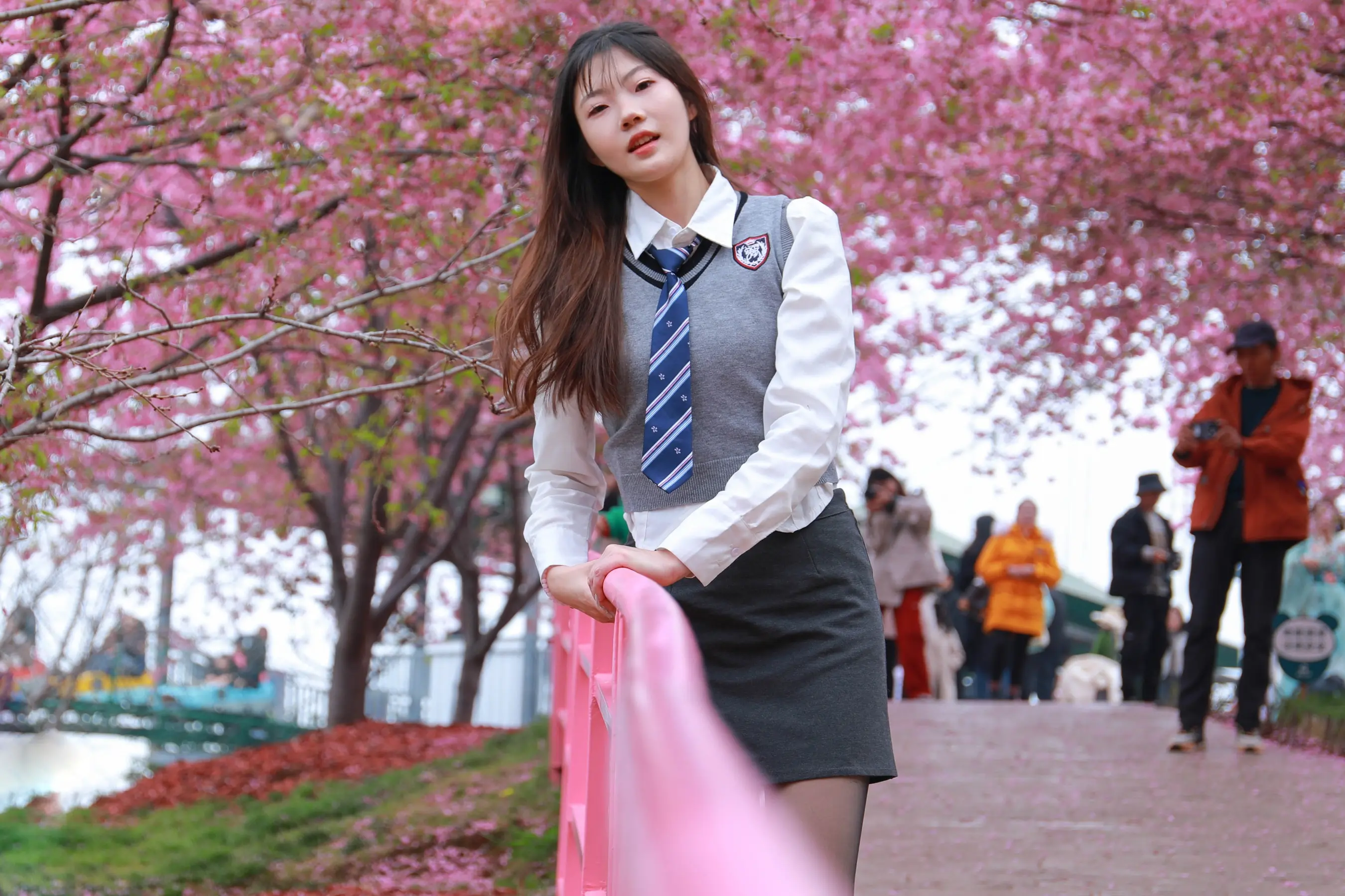有个穿着校服的女人，手里拿着一条粉红色的围巾