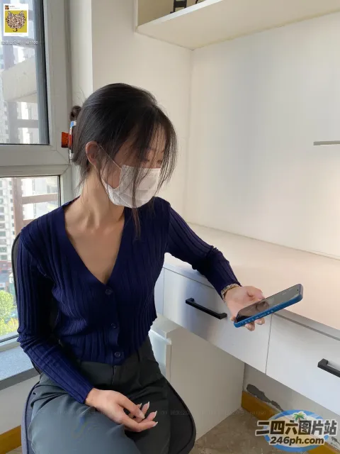 戴着口罩和手机坐在桌子上的女人