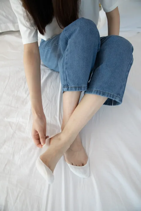 坐在床上，双脚放在枕头上的阿拉菲德女人