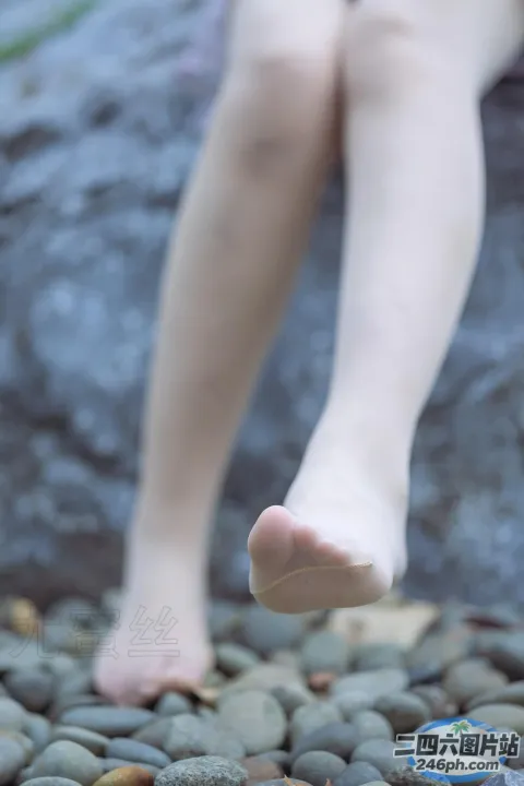 有一个人坐在一块石头上，双脚抬起