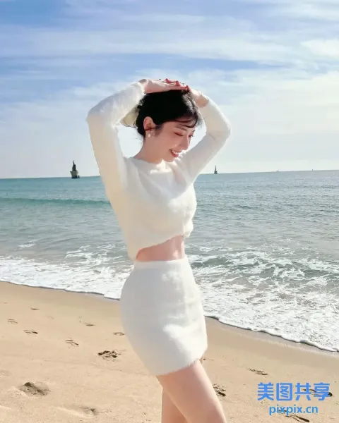 一个穿着白色连衣裙的女人站在海边的海滩上