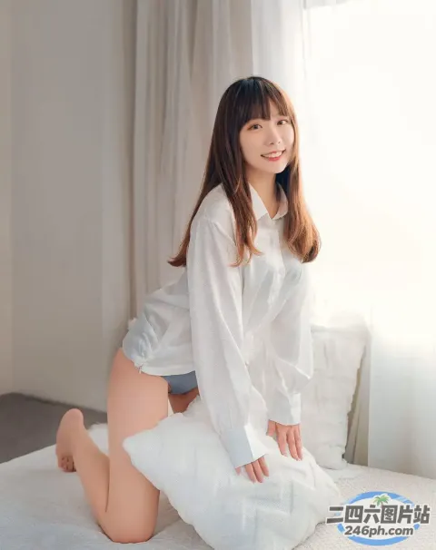 一个穿着白衬衫和短裤的女人坐在床上