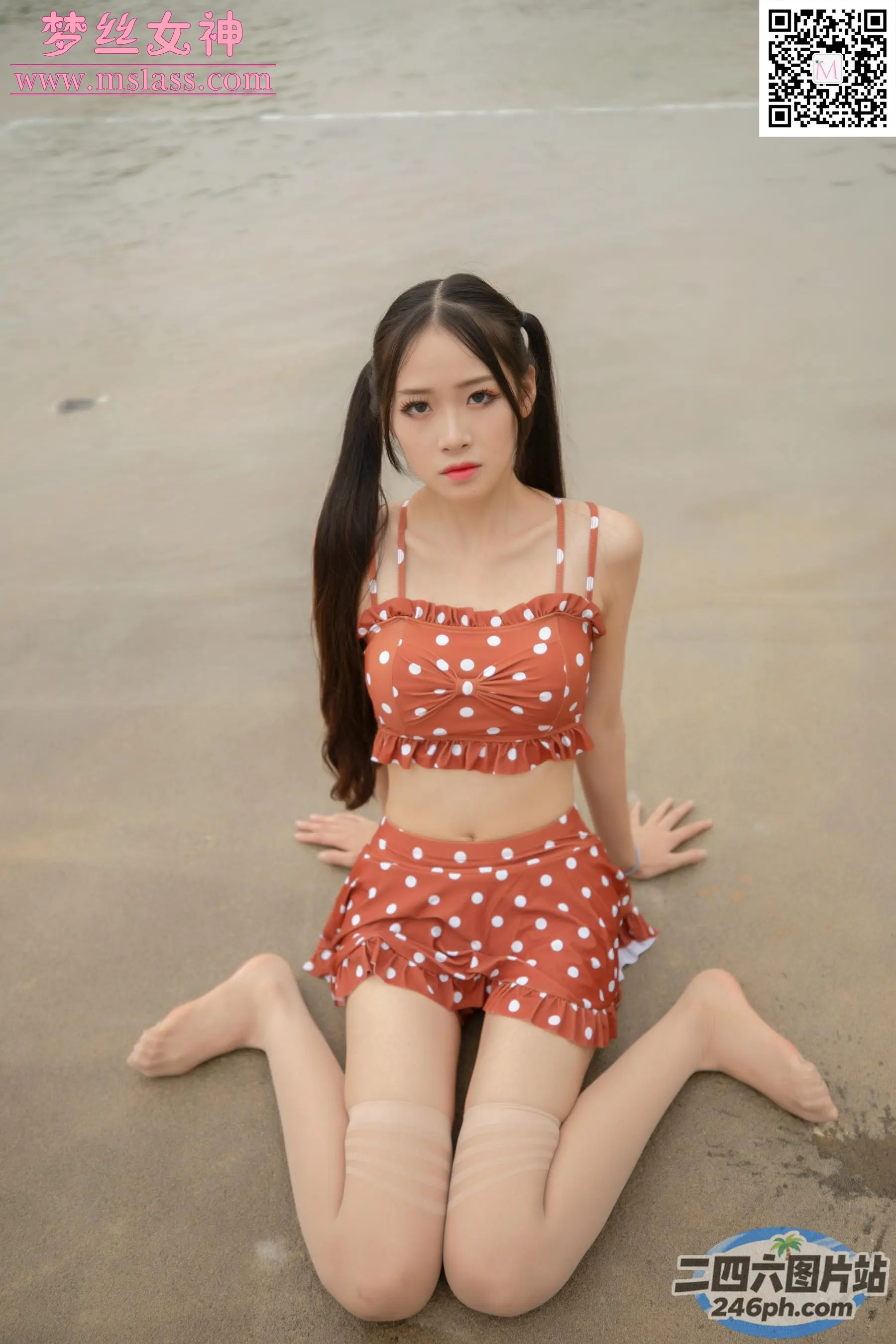 一位穿着波点上衣和短裤的女人坐在海滩上