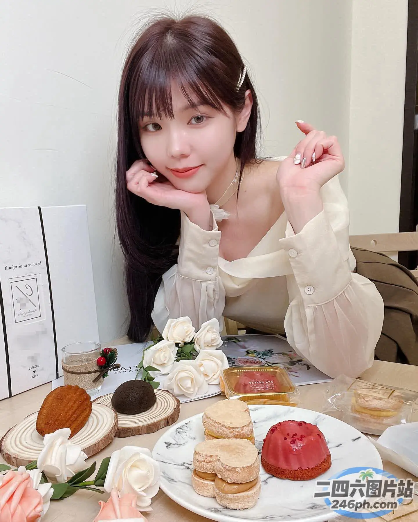 有个女人坐在桌子旁，手里拿着一盘甜品