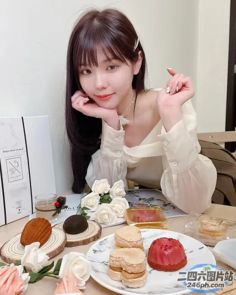有个女人坐在桌子旁，手里拿着一盘甜品