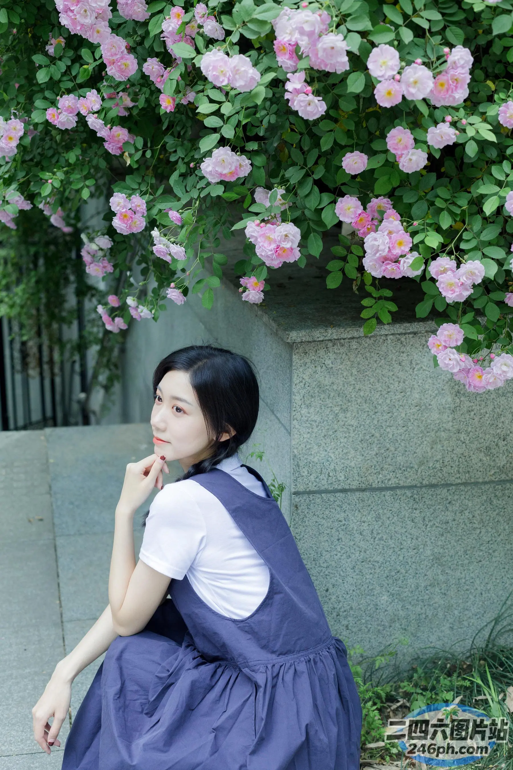 有一个女人坐在一丛花丛前的地上