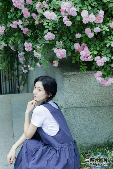 有一个女人坐在一丛花丛前的地上