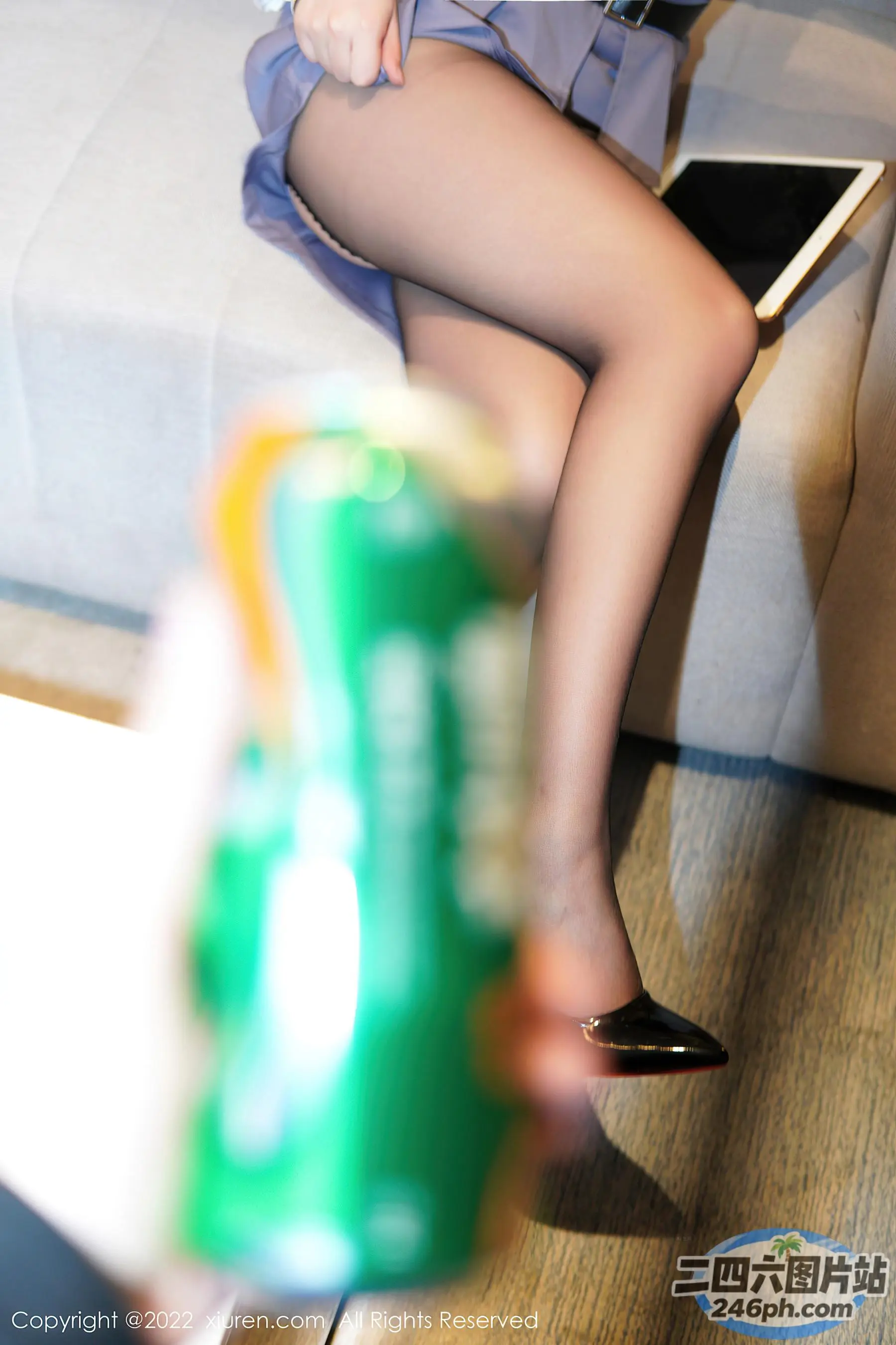 坐在沙发上的女人，手里拿着一罐苏打水和一台笔记本电脑