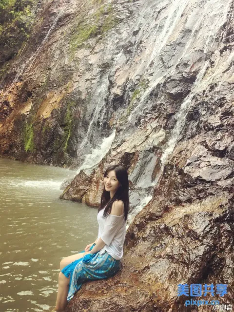 坐在瀑布前岩石上的阿拉夫女人