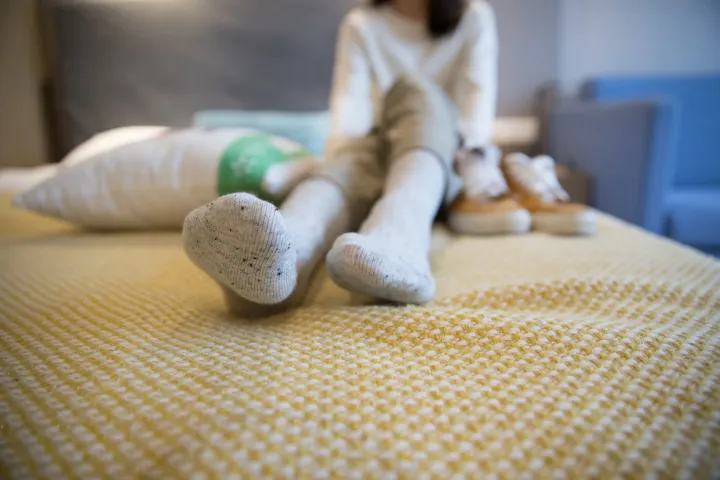 有一个女人坐在床上，手里拿着一个毛绒玩具