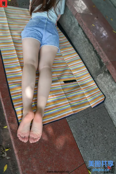 阿拉夫女孩躺在地上的毛巾上，双脚抬起