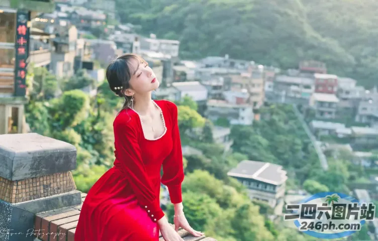 身穿红裙的 araffe 女子坐在俯瞰城市的窗台上