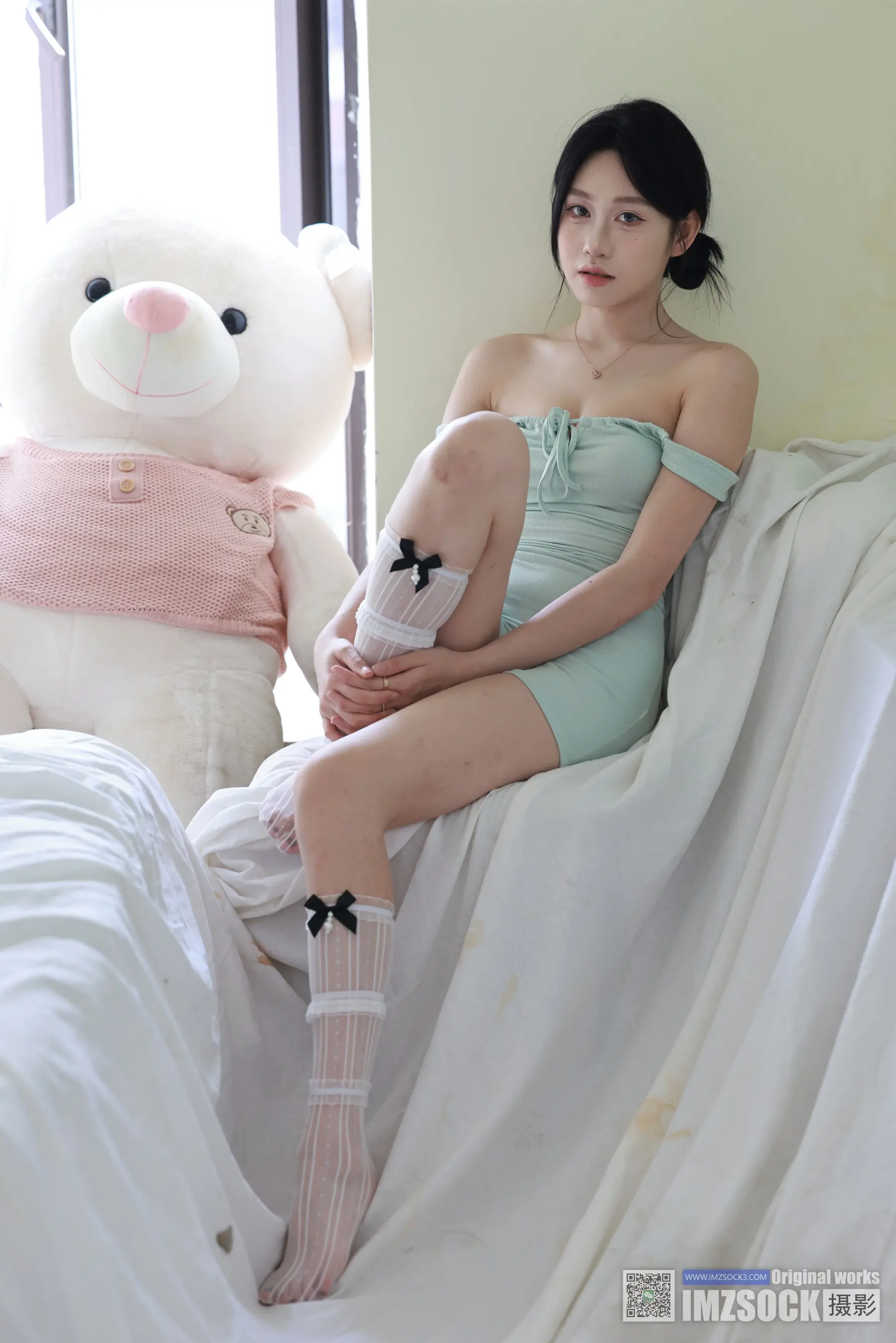 Araffe 坐在床上，手里拿着一只泰迪熊和一条裙子