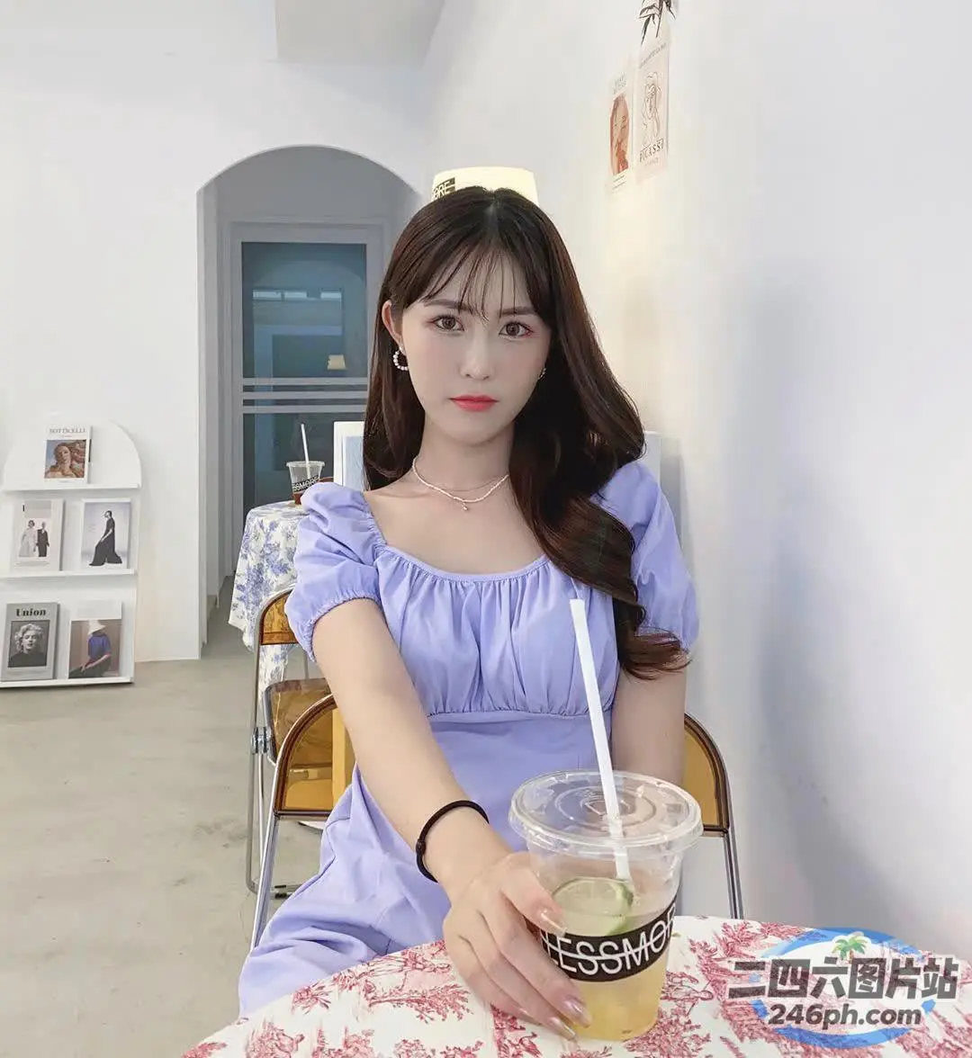 有个女人坐在桌子旁，手里拿着一杯饮料
