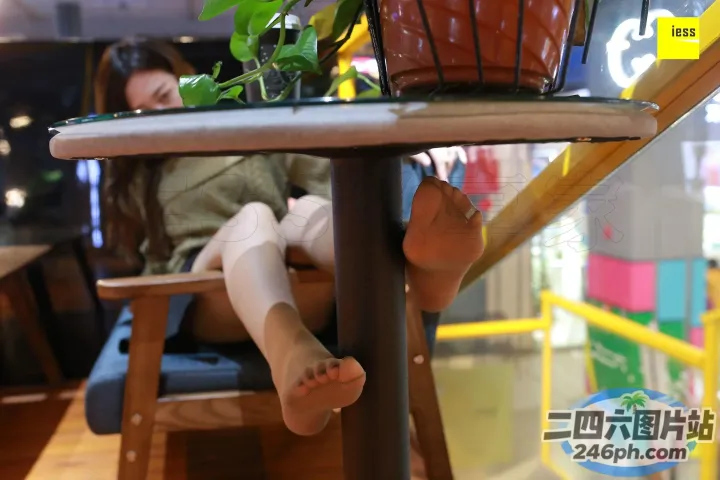 有个女人坐在一张桌子旁，桌上放着一棵植物