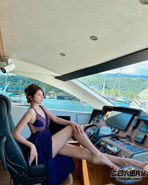 穿着蓝色连衣裙的女人坐在船上，手里拿着电脑