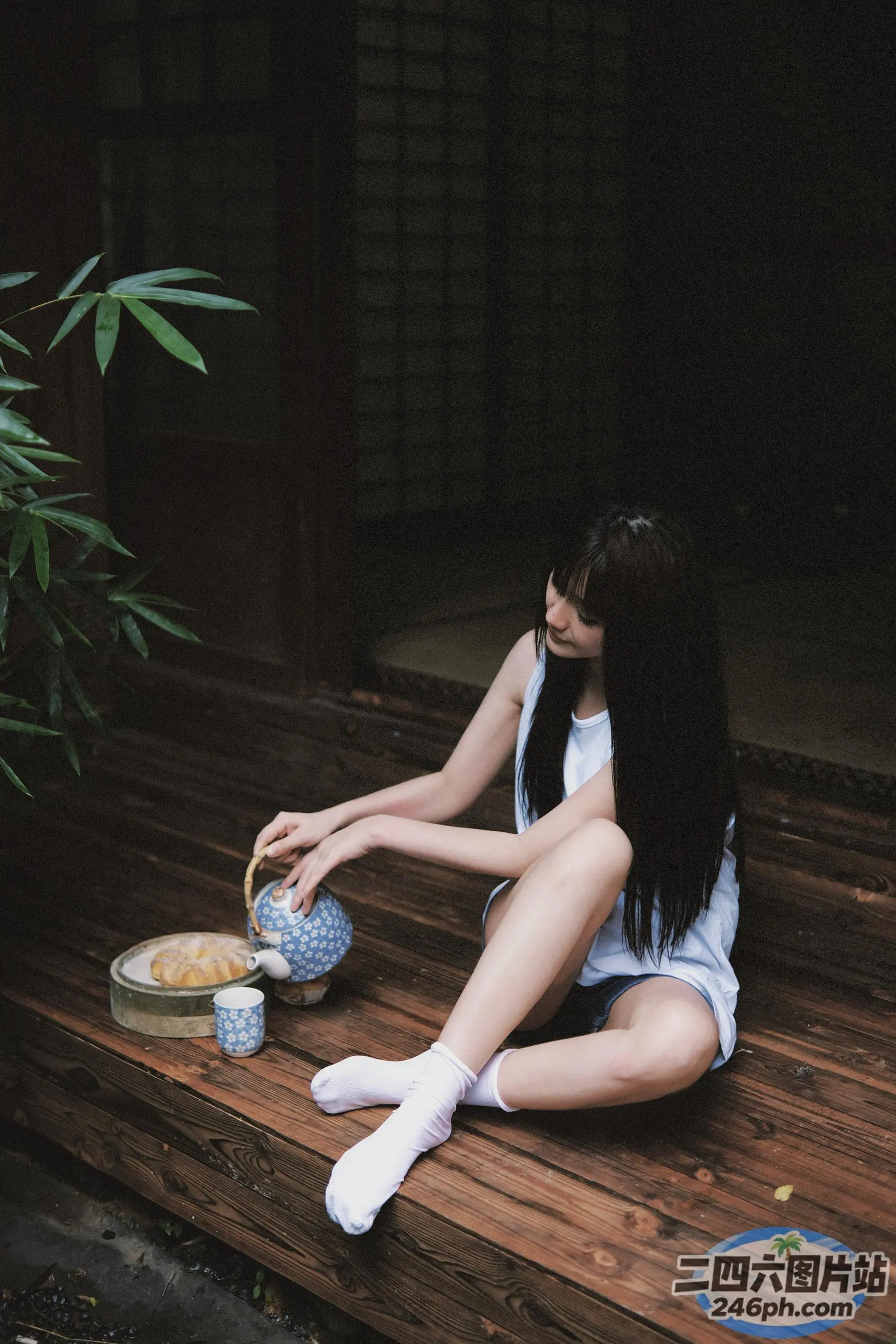 阿拉菲女人坐在木制门廊上，手里拿着茶壶和碗