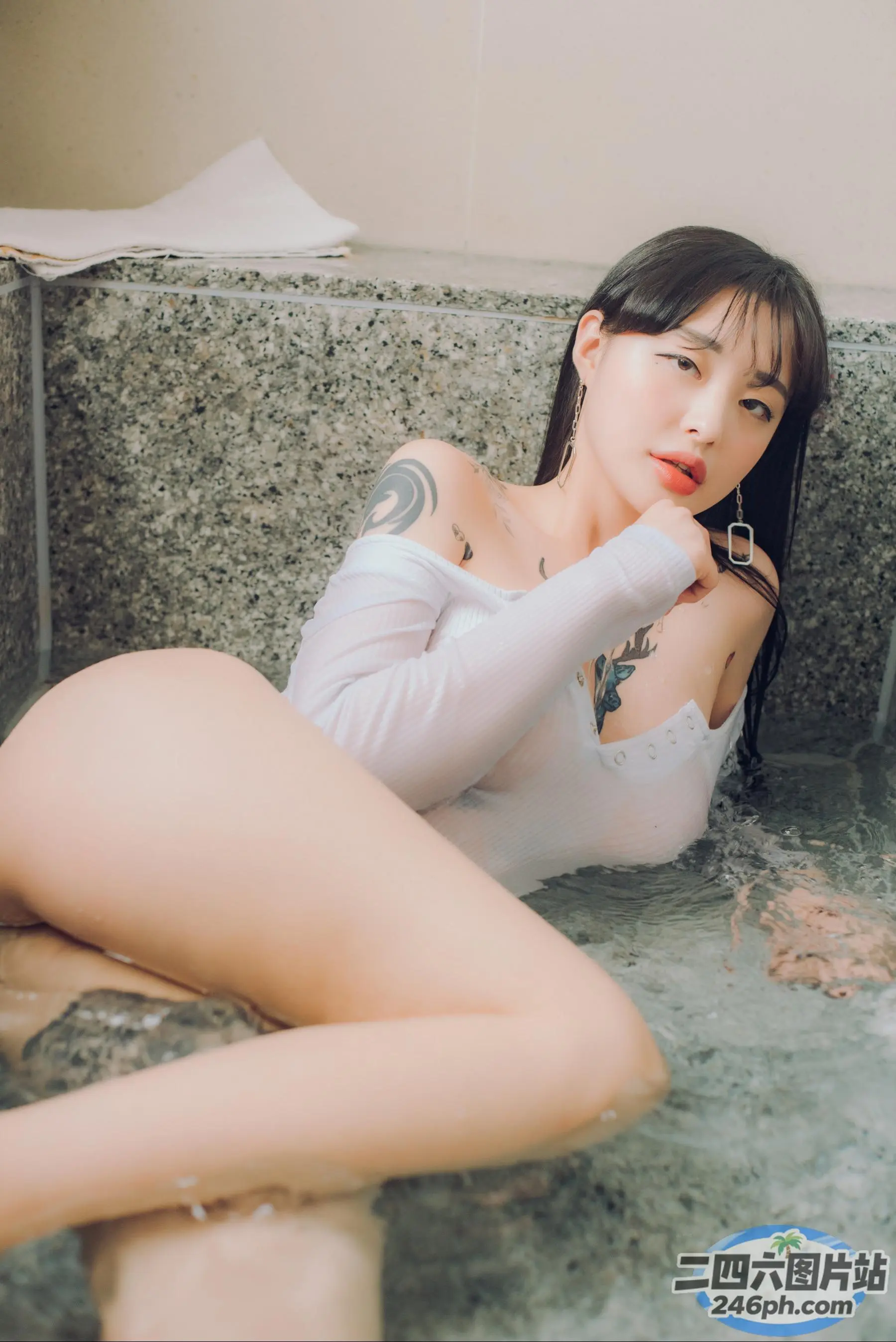 Araffe 亚洲妇女在浴缸里，手臂上有纹身