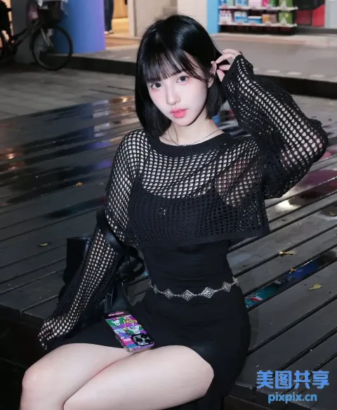 一位身穿黑色连衣裙坐在长凳上的女人的特写