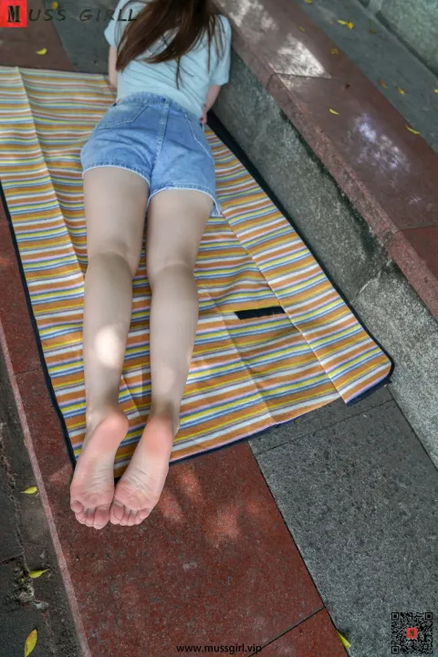 阿拉夫德女人躺在人行道上的毛巾上，双脚抬起