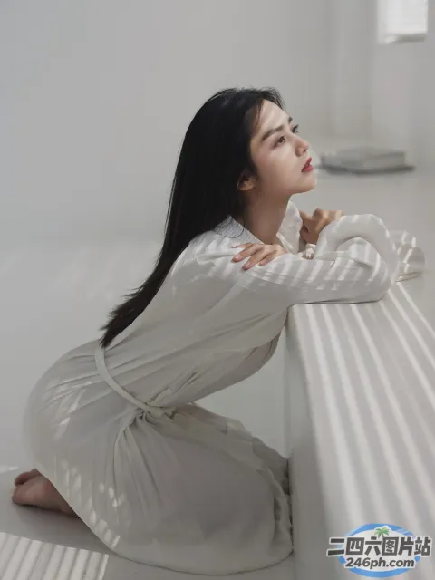 一个女人坐在白色房间的长凳上