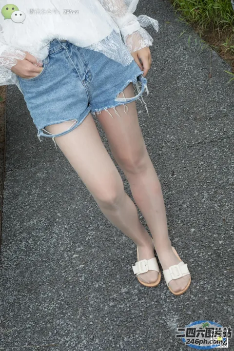 有个女人站在人行道上，双腿交叉