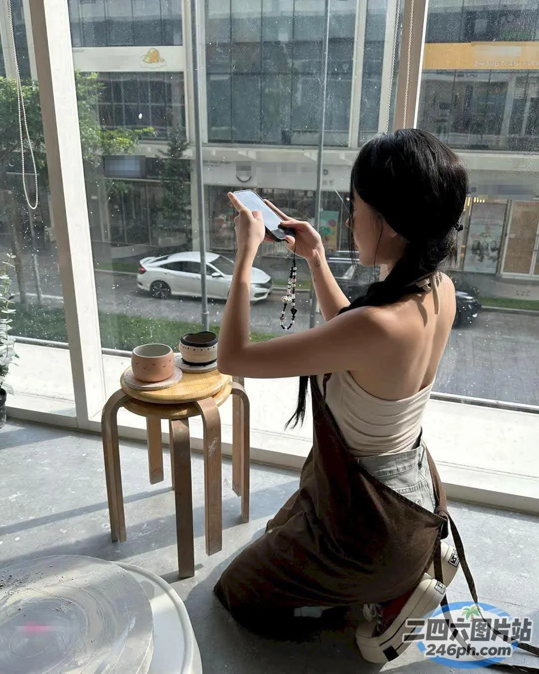 坐在窗前地板上使用手机的女人