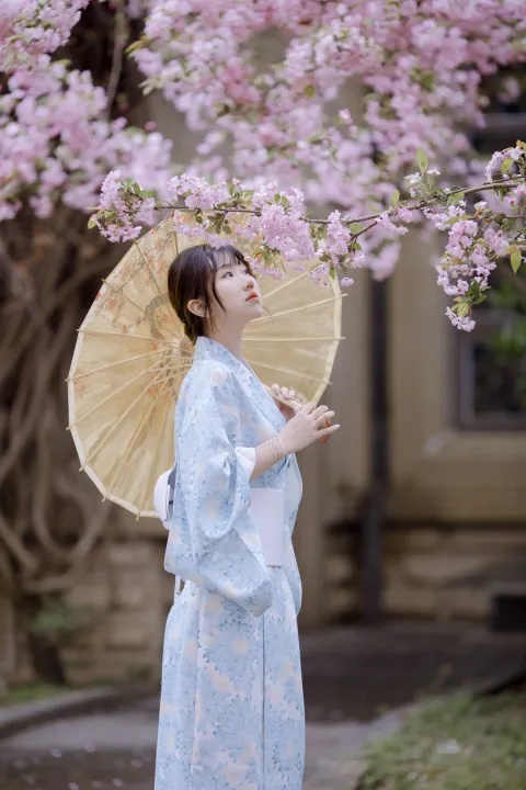 身穿蓝色和服，撑着黄色雨伞的 araffe 女子