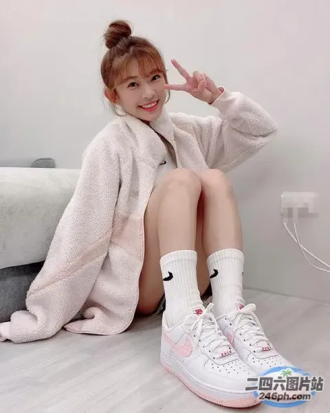 一个女人坐在地板上，双腿交叉，头上套着一件白色夹克