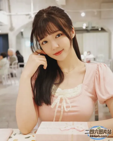 阿拉菲女人坐在桌子旁，手里拿着一盒饼干
