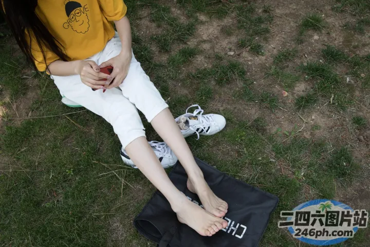 有一个女人坐在地上，脚放在一个袋子上