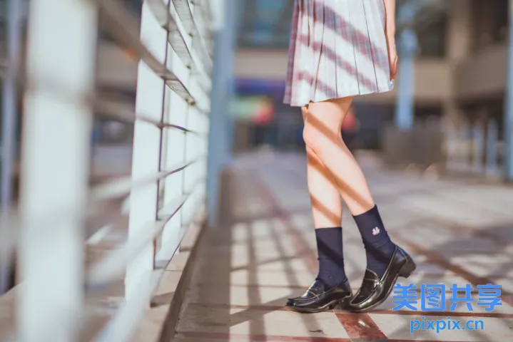人行道上站着一个穿着裙子和袜子的女人