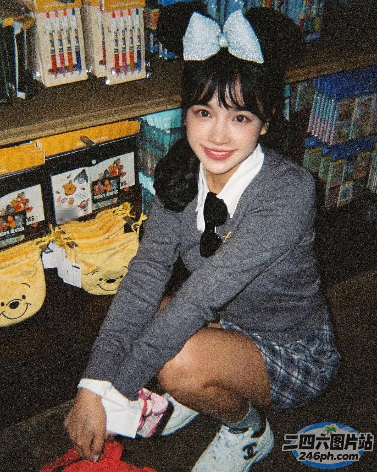 有一个穿着校服的女孩跪在地上，手里拿着一个红色的飞盘