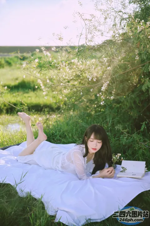 阿拉菲女人躺在田野里的毯子上，手里拿着一本书