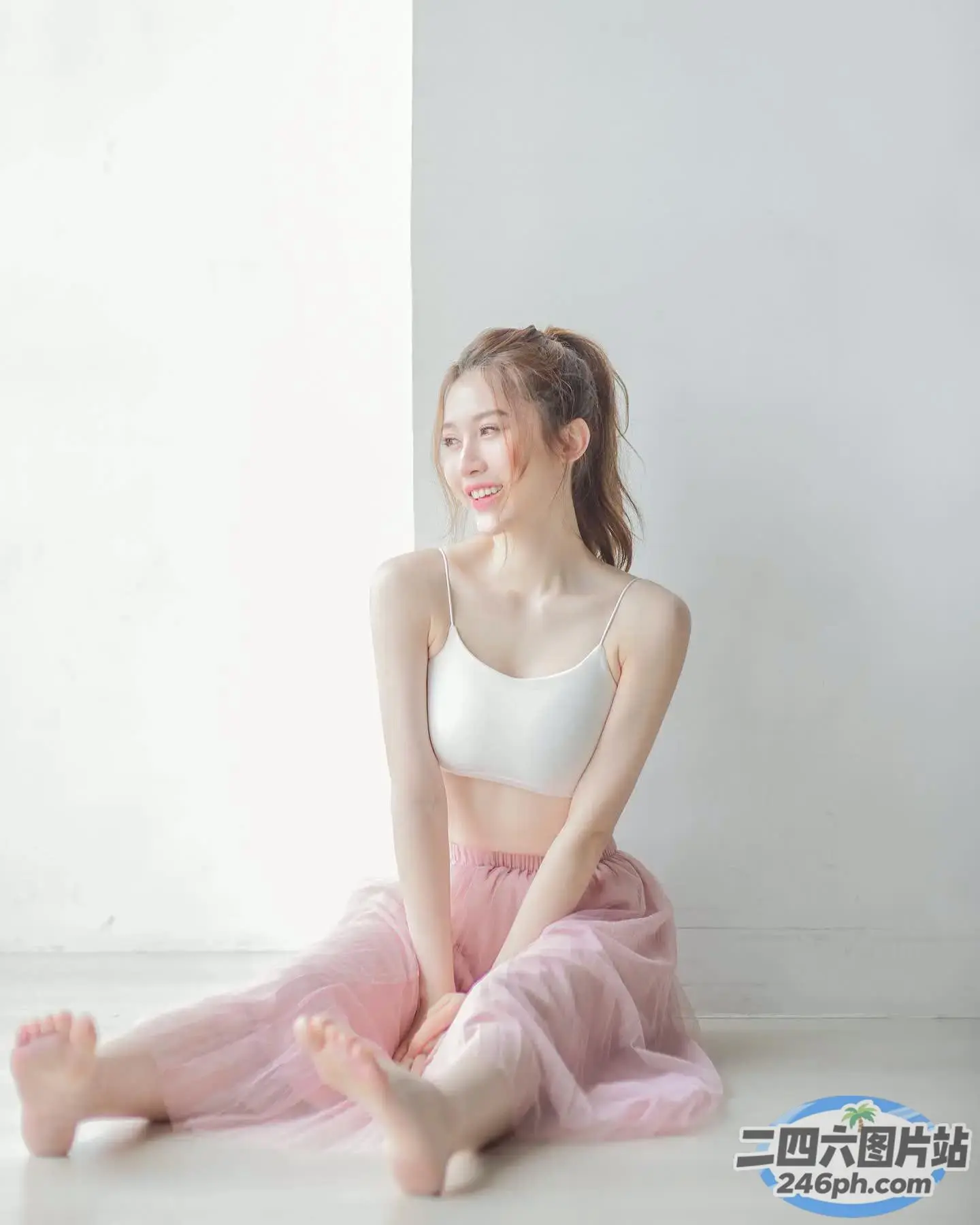 一位身穿粉红色芭蕾舞裙的女士坐在地板上