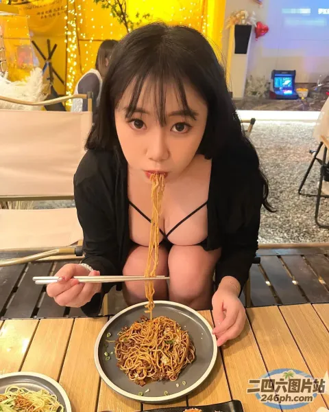 阿拉伯裔亚洲妇女在桌子上用筷子吃面条