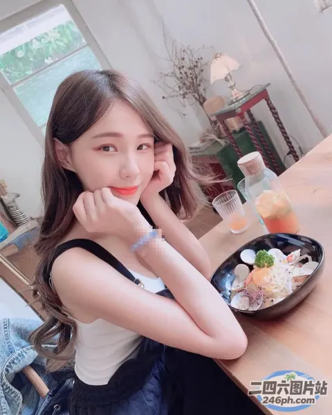 一位女士手里拿着一碗食物坐在桌子旁