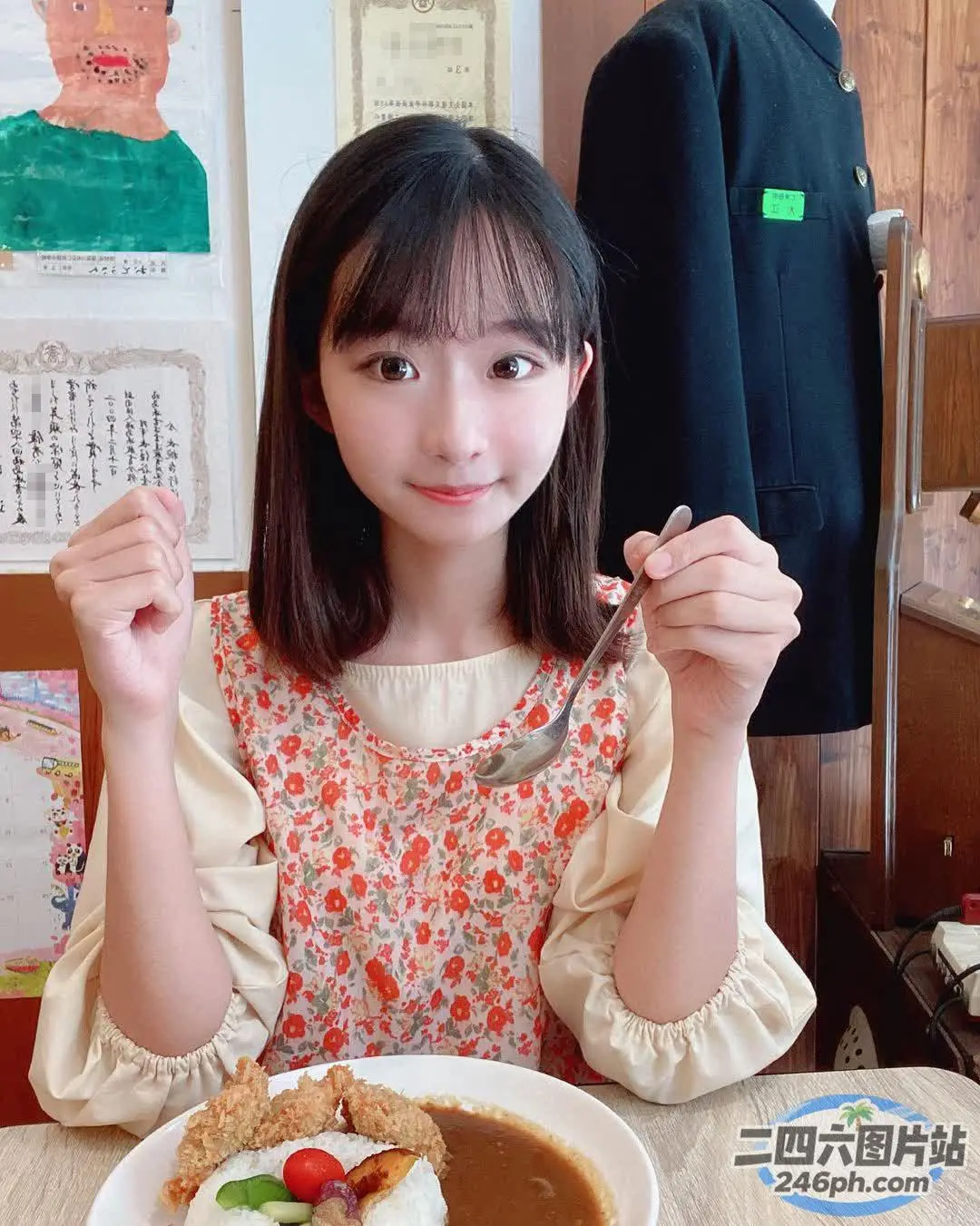 阿拉菲女孩坐在桌子旁，手里拿着一盘食物和一把叉子