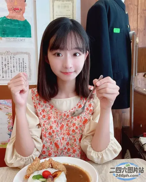 阿拉菲女孩坐在桌子旁，手里拿着一盘食物和一把叉子