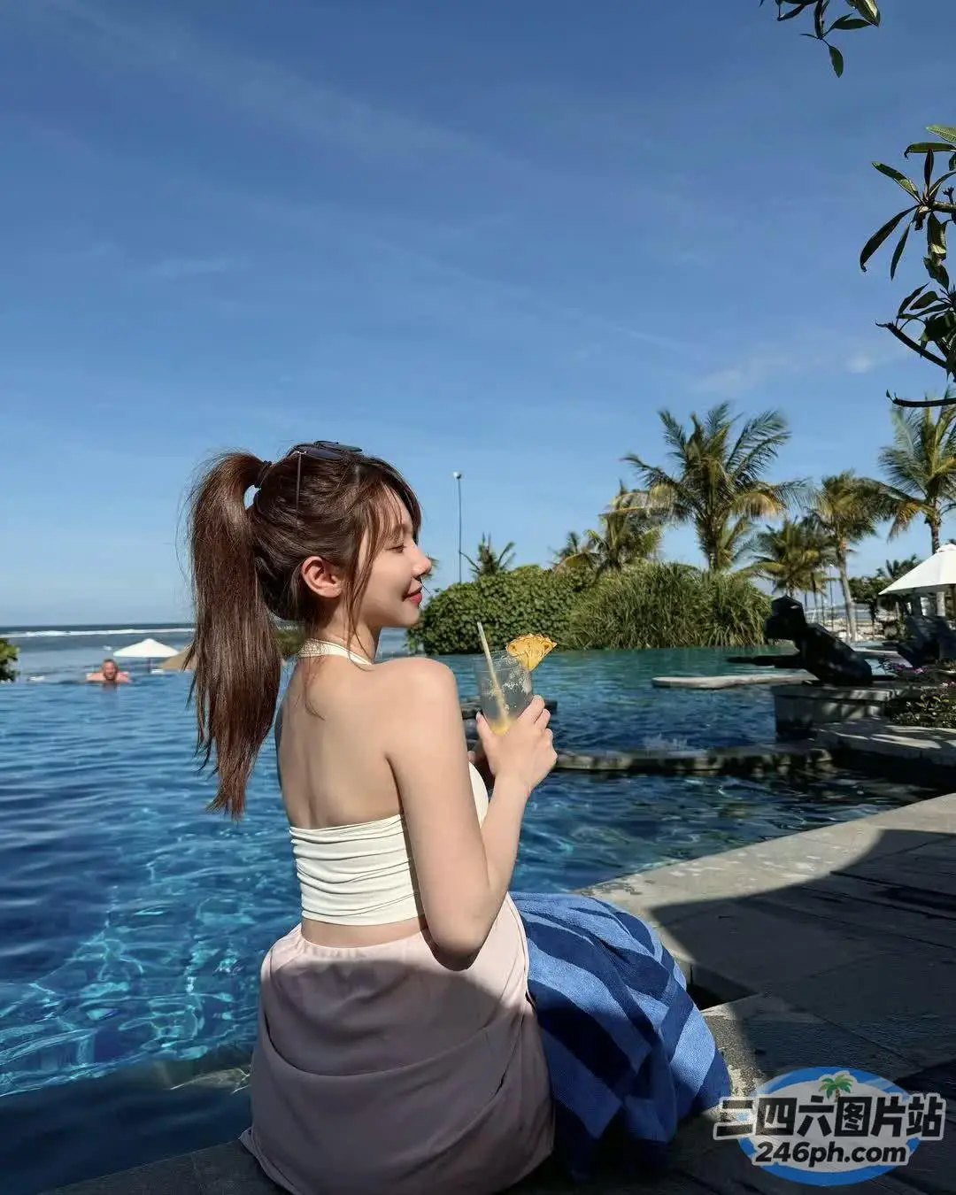 阿拉夫德女人坐在游泳池旁边的窗台上，喝着饮料
