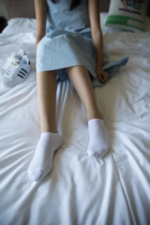 坐在床上，穿着白色袜子的 Araffed 女人