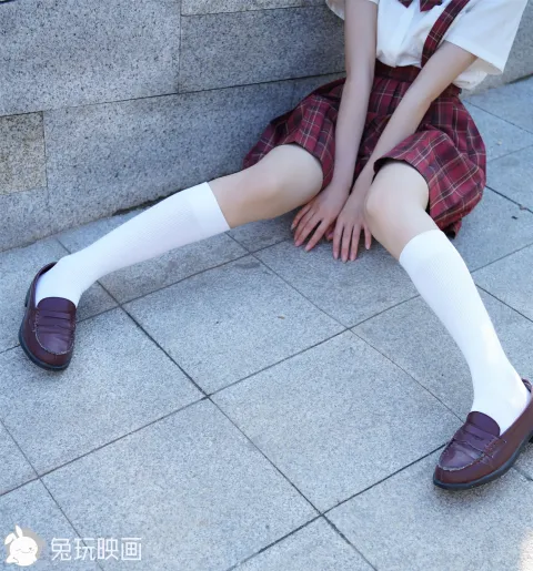 穿着校服坐在墙上的 arafed 亚裔妇女