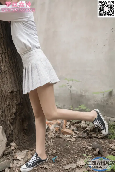 一个女人双腿交叉靠在树上的特写